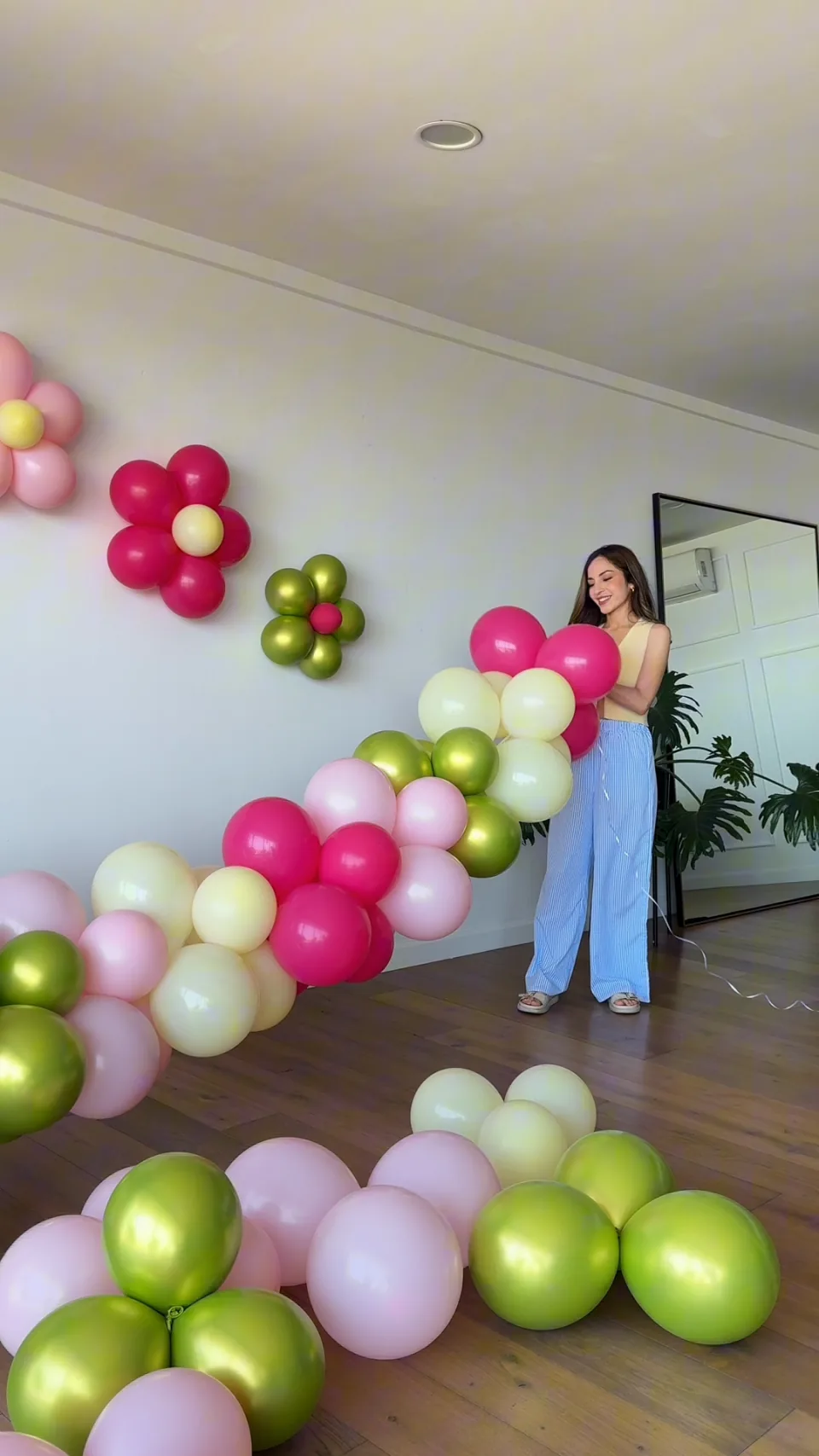 Ariane sosteniendo una guirnalda orgánica fucsia, rosa, crema y verde lima