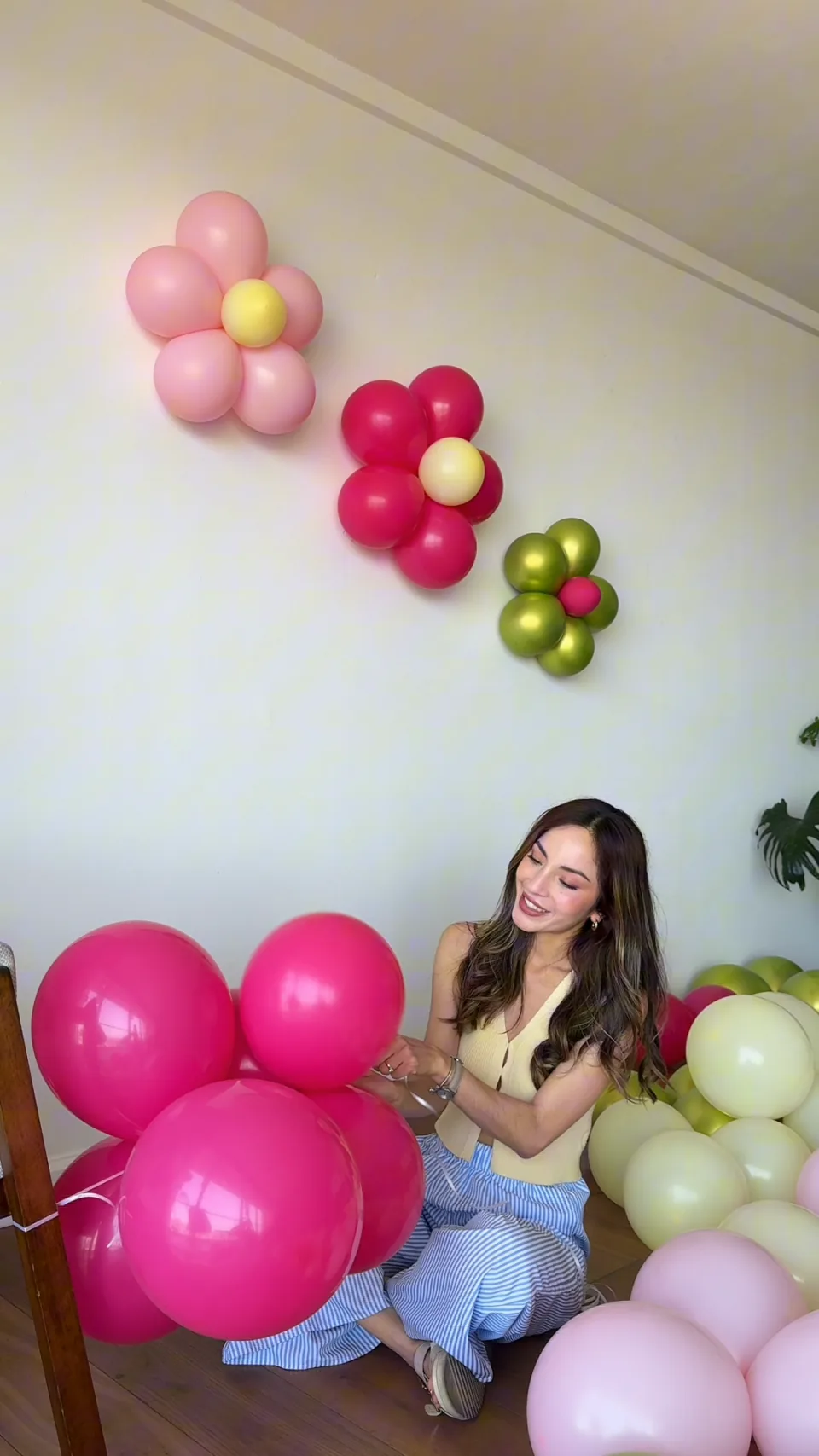 Ariane sonriendo mientras combina globos fucsia, rosa y verde lima